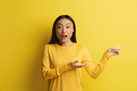 Surprised Woman Pointing Aside. Amused Young Girl Points Finger Awayの写真素材