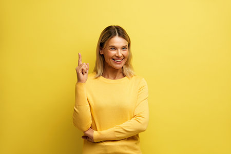 Cheerful Woman Pointing Up at Studio. Overjoyed Girl Points Finger Empty Spaceの写真素材
