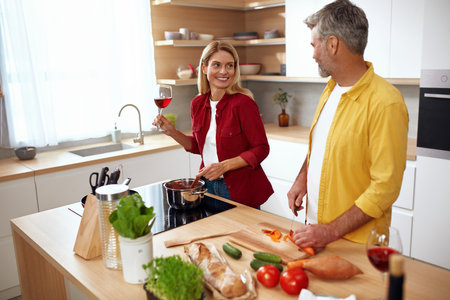 Couple Cooking Kitchen. Senior Man Cutting Vegetables While Wife Drinking Wineの写真素材