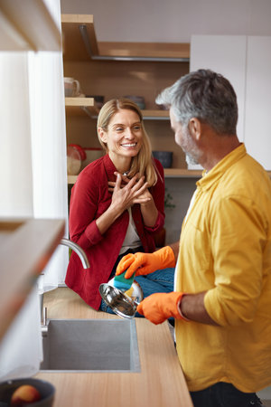 Senior Couple Cleaning Dishes At Kitchen. Vertical Shot of Man Washing Dishesの写真素材