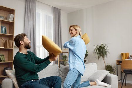Couple Fighting Pillows At Home. Happy Young Couple Fighting On Pillowsの写真素材