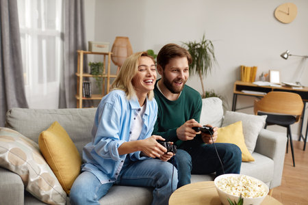 Happy Couple Playing Video Games. Boyfriend And Girlfriend Sitting On Couchの写真素材