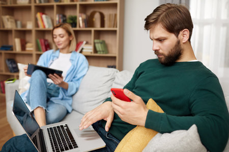 Couple Using Gadgets At Home. Married Couple Of Freelancers Work From Homeの写真素材