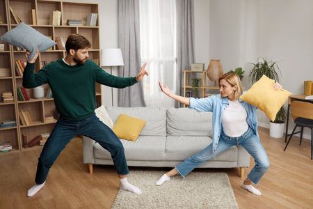 Couple Fighting Pillows At Home. Happy Young Couple Fighting On Pillowsの写真素材