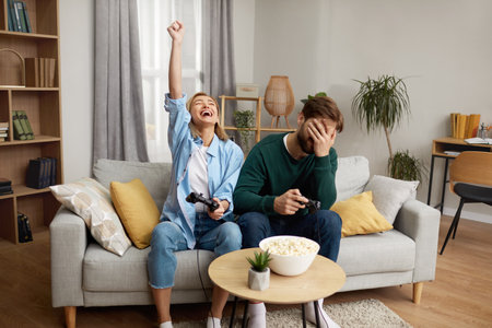 Young Couple Playing Video Games. Focused Boyfriend Girlfriend Sitting On Couchの写真素材