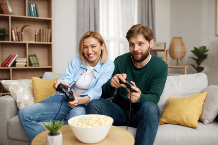 Happy Couple Playing Video Games. Boyfriend And Girlfriend Sitting On Couchの写真素材