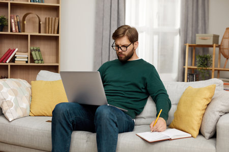 Serious Man Working Laptop. Bearded Guy Work At Notebook At Homeの写真素材