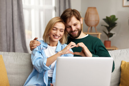 Couple Using Laptop Computer, While Sitting On The Living Roomの写真素材