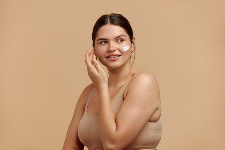 Positive Woman Applying Face Cream. Female Model Applying Cosmetic Productの写真素材