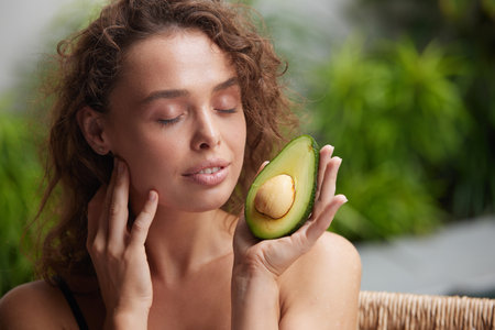 Smiling Woman Holding Avocado. Beautiful Happy Woman With Smooth Soft Clean Skinの写真素材