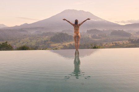 Woman Meditating at Resort Pool in Bali Agung Volcano - Best Travel Destinationの写真素材