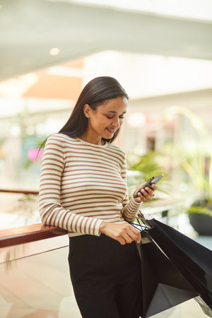 Happy Woman Holding Smartphone for Weekend Shoppingの写真素材