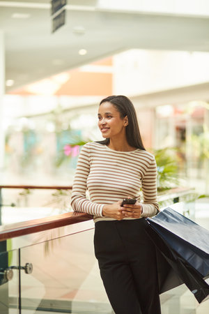 Happy Young Woman Shopping for Trendy Outfits at Boutique Saleの写真素材
