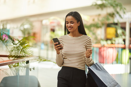Happy Woman Holding Smartphone, Shopping at Trendy Boutiqueの写真素材