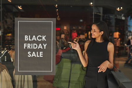 Happy Woman Pointing at Sale in Diverse Fashion Storeの写真素材