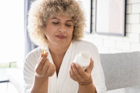 Woman Healthcare. Female Holding Pills and Bottle in a Bright Roomの写真素材
