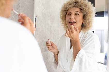 Young Woman in Morning Skincare Routine Applying Lipstickの写真素材