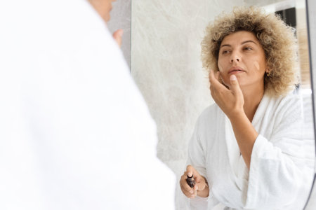 Young Adult Woman in Morning Skincare Routine at Homeの写真素材