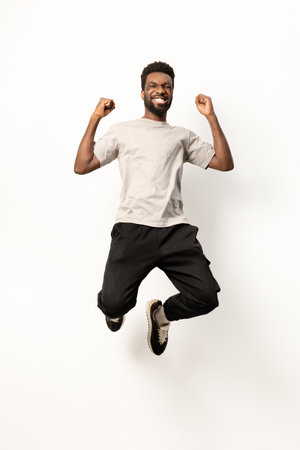 Joyful African American Man Jumping with Excitement in Studioの写真素材