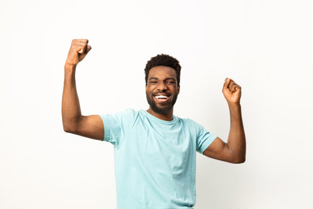 Joyful African American Man Celebrating Success with Arms Raisedの写真素材