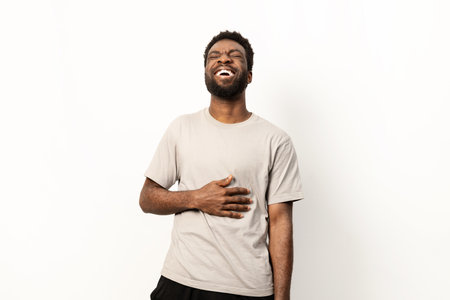 Joyful African Man Laughing with Hands on Stomachの写真素材