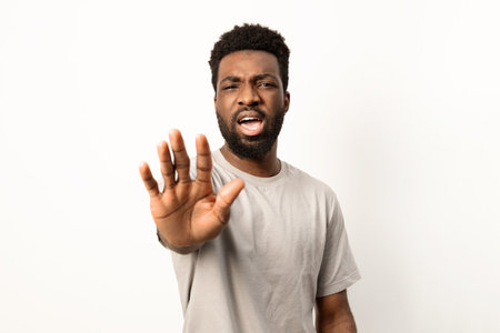 Young Man Expressing Stop Gesture on White Backgroundの写真素材