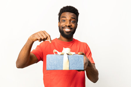 Afro American Man Smiling and Pointing at Gift Box on Whiteの写真素材