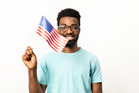 Smiling African American Man Holding American Flag Isolated on Whiteの写真素材