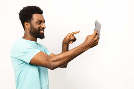 African American Man Using Tablet with Joyful Expression Isolated on Whiteの写真素材