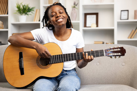 Woman Enjoying Music Playing Guitar at Homeの写真素材