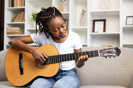 Afro American Woman Playing Acoustic Guitar at Home on Couchの写真素材