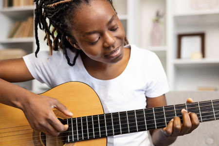 African American Woman Enjoying Music Practice with Guitar at Homeの写真素材