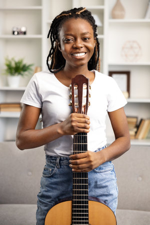 Happy African American Woman Playing Guitar at Homeの写真素材