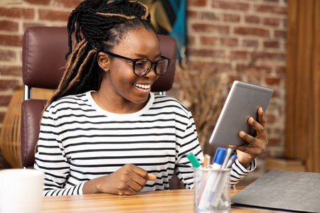 Smiling Woman Enjoying Video Call on Tablet at Home Officeの写真素材