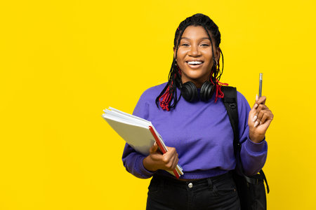 Student with Books and Headphones on Yellow Backgroundの写真素材