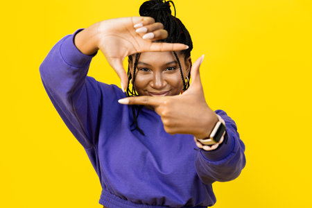 Happy Woman Framing with Hands On Yellow Backgroundの写真素材