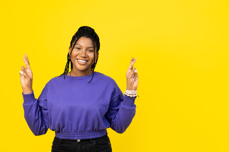 Afro woman makes a wish on yellow backgroundの写真素材