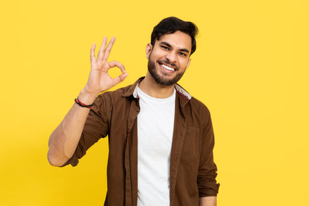 Young Man Making Positive Hand Gesture On Yellow Backgroundの写真素材