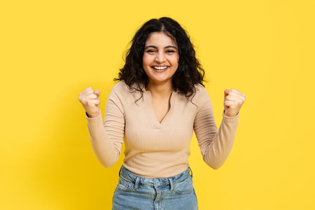 Woman Celebrating Success On Yellow Backgroundの写真素材
