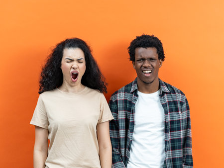 Young Couple Expressing Emotions Against Orange Backgroundの写真素材