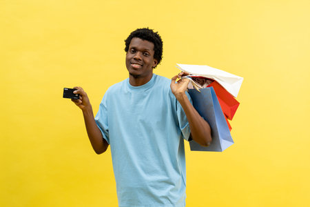 Happy Man Holding Credit Card And Shopping Bags On Yellow