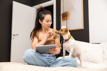 Young Woman With Tablet Enjoying Time with Her Dog at Homeの写真素材