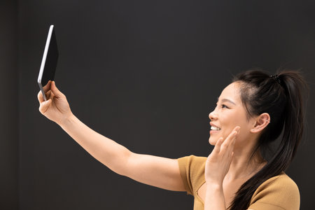 Woman Holding Tablet Against Dark Backgroundの写真素材