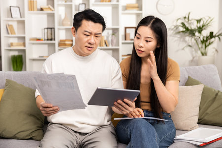 Couple Analyzing Documents and Digital Tablet on Sofaの写真素材