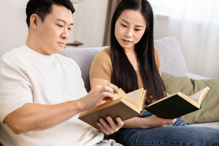 Couple Reading Books on Sofa in a Cozy Homeの写真素材