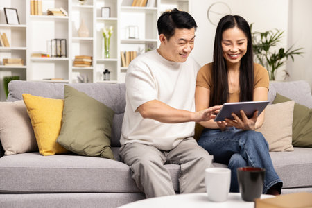 Happy Couple Browsing Internet Together on Tablet at Homeの写真素材