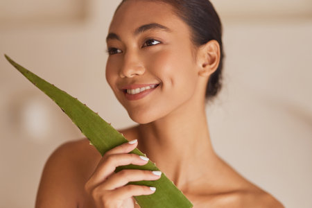 Skincare Beauty Aloe. Smiling Woman Holding Aloe Vera Leaf for Natural Skincare Routineの写真素材