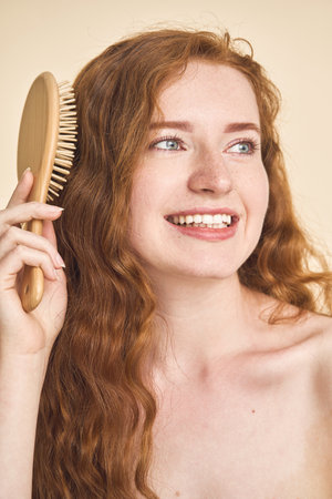 Woman Brushing Long Red Hair With Wooden Hairbrushの写真素材