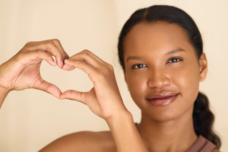 Smiling Woman Making Heart Shape with Hands, Symbolizing Love and Positivityの写真素材