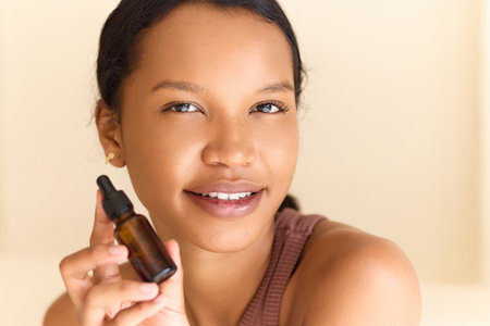 Skincare Serum. Woman Smiling While Holding Skincare Serum Bottle in Neutral Settingの写真素材